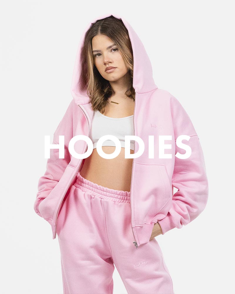 Kobieta w różowej bluzie z kapturem i dresach marki Looking, na białym tle. Na środku napis hoodies